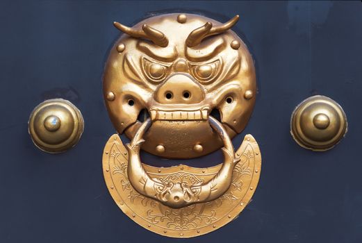 Golden colored chinese door knocker on a blue door, China