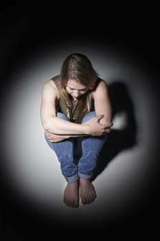 Unhappy Young Woman Sitting In Pool Of Light