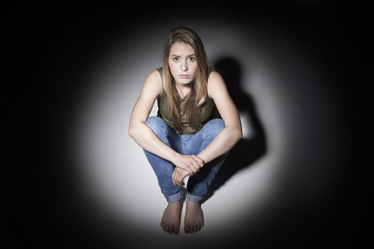 Sad Woman Sitting In Pool Of Light