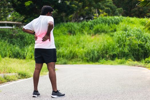 Close up Asian young sport runner black man wear watch feel pain on his spine low back and hip while running at the outdoor street health park, healthy exercise Injury from workout concept