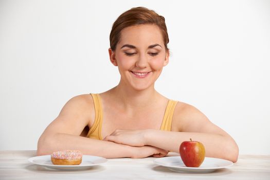 Young Woman Choosing Between Doughnut And Cake For Snack