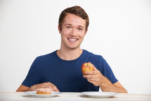 Young Man Choosing Between Doughnut And Cake For Snack