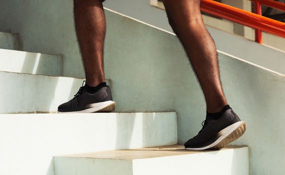 Close up athlete shoes of legs young sport runner black man step running up to climbing stairs doing training cardio sport workout at the outdoor street, healthy exercise before workout concept