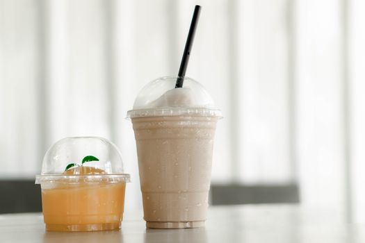 Close up glass of ice americano coffee and orange cake on wood table, selective focus