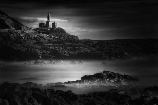 The Mumbles with it's lighthouse as seen from Bracelet Bay on the Gower Peninsular Wales, UK black & white monochrome image