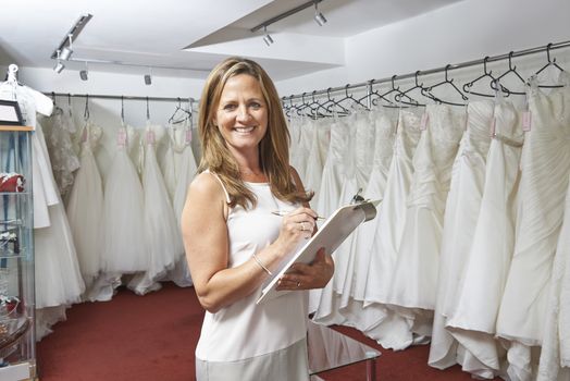 Portrait Of Female Bridal Store Owner With Wedding Dresses
