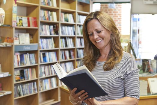 Female Customer Reading Book In Bookstore