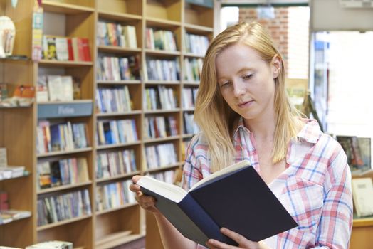 Young Woman Reading Book In Bookstore