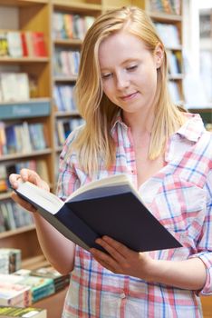 Young Woman Reading Book In Bookstore