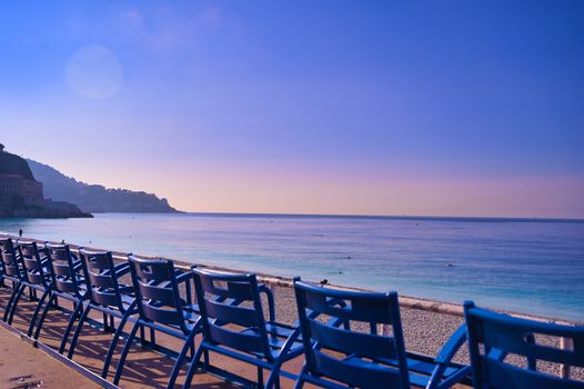 Blue chairs along the Promenade des Anglais on the Mediterranean Sea at Nice, France along the French Riviera.