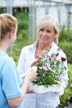 Staff Giving Plant Advice To Female Customer At Garden Center