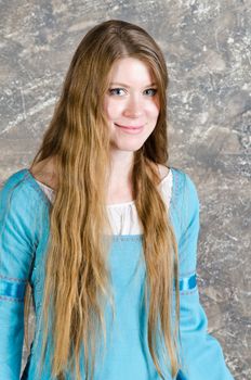 Pretty young woman in historical medieval blue dress poses in studio