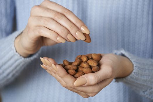 Close Up Of Woman Holding Handful Of Almonds