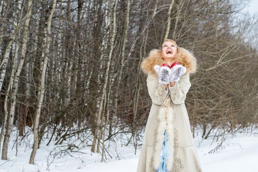 Sincerely laughing young woman in a winter forest with apples in her hands