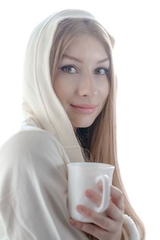 Romantic sensual teenager in a white hood is sitting with a mug in front of a window