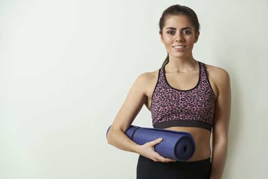 Young Woman In Sportswear Carrying Exercise Mat