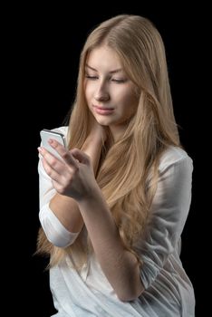 Young pretty girl enjoying chat over internet on her personal cellular mobile phone. Isolated on black.