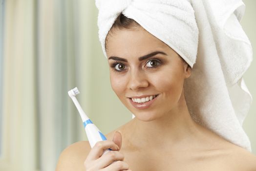 Woman Brushing Teeth With Electric Toothbrush In Bathroom