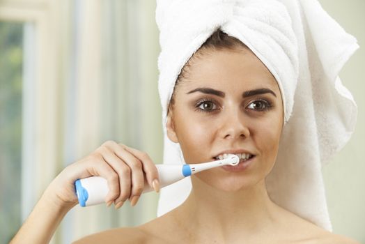 Woman Brushing Teeth With Electric Toothbrush In Bathroom