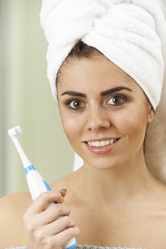 Woman Brushing Teeth With Electric Toothbrush In Bathroom