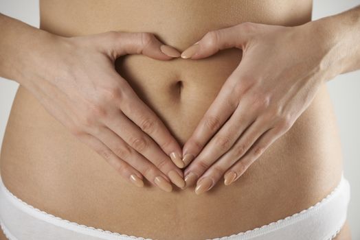Close-Up Of Woman Making Heart Shape With Hands On Stomach