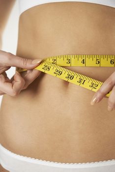 Close-Up Of Woman In Underwear Measuring Waist With Tape