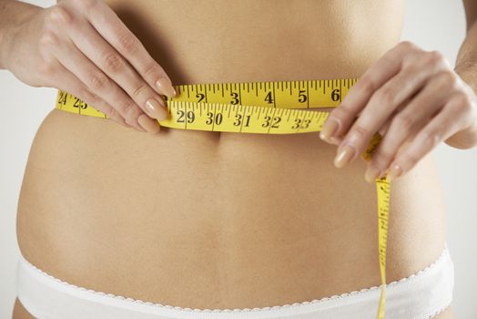 Close-Up Of Woman In Underwear Measuring Waist With Tape