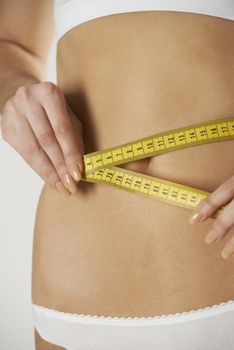 Close-Up Of Woman In Underwear Measuring Waist With Tape