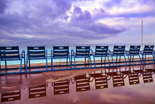 Blue chairs along the Promenade des Anglais on the Mediterranean Sea at Nice, France along the French Riviera.