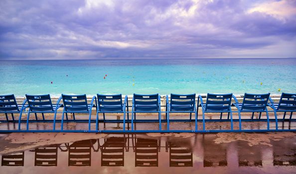 Blue chairs along the Promenade des Anglais on the Mediterranean Sea at Nice, France along the French Riviera.