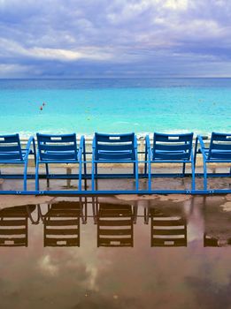 Blue chairs along the Promenade des Anglais on the Mediterranean Sea at Nice, France along the French Riviera.