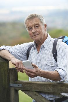 Senior Man Checking Location With Mobile Phone On Hike