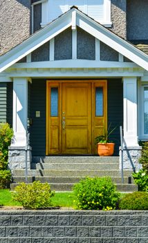 Doorsteps to the entrance of family house with landscaped front yard.