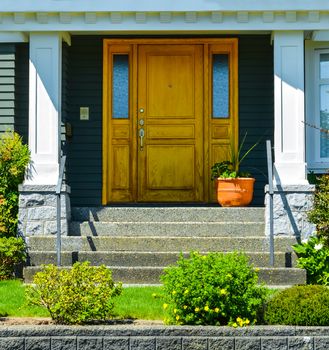 Doorsteps to the entrance of family house with landscaped front yard.