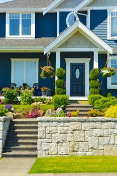 Entranc of luxury family house with landscaped front yard on land terrace. Family house on blue sky background