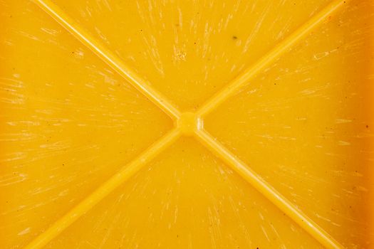 close-up texture and background of yellow bakelite or carbolite plastic material with x-shaped mold ribs.