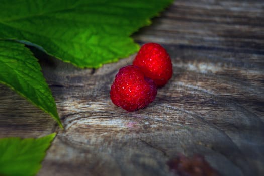 Raspberries close up view. Macro photo raspberry. Natural ripe organic berries with peduncles, green leaves, top view, flat lay with copy space.