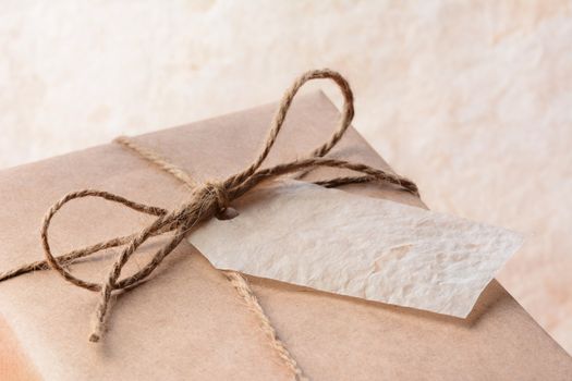 Closeup of a brown eco friendly paper wrapped package with gift tag. Horizontal format with shallow depth of field.