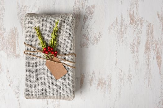 Fabric Wrapped Christmas Present on a rustic whitewashed wood surface. Horizontal with copy space.