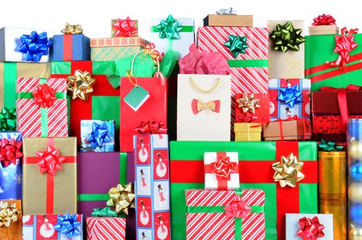 Close up of a large stack of wrapped Christmas presents of varying sizes and shapes with white space at the top. Vertical format with the frame filled from side to side.