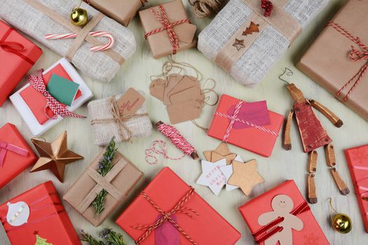 Christmas Gifts, tags, and wrapping supplies on a rustic wood table. Horizontal format from a high angle.