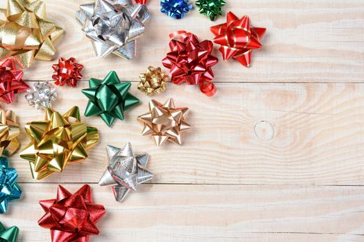 High angle shot of colorful holiday bows on a whitewashed rustic wood table. Horizontal format with copy space.