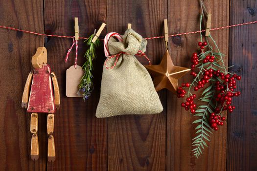 Christmas Gift bag and decorations hanging from twine against a rustic dark wood wall.