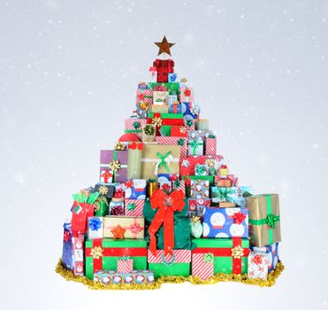 A Christmas tree shape made up of many stacked presents, on a light to dark snowy background.