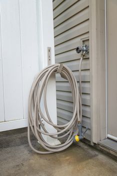 Vertical shot of a rolled up and hung patio garden hose.