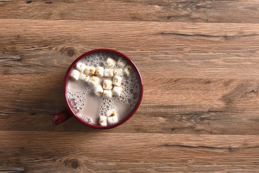 Top view of a single mug of hot cocoa with marshmallows on a rustic wood table.