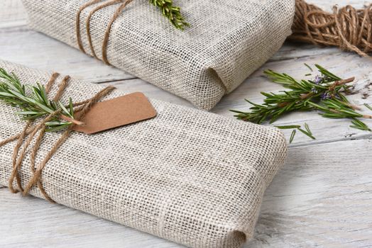 Closeup of two fabric wrapped Christmas presents on a rustic wood table.