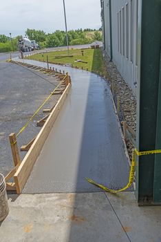 Vertical shot of a new concrete sidewalk that has just been poured with framing.