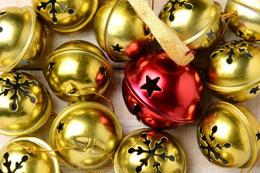 Closeup of a group of gold silver bells with one red one in the middle. The jingle bells fill the frame.