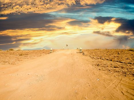 Empty dirt road with barren desert on both sides and blue sky above showing thar desert of rajasthan india.